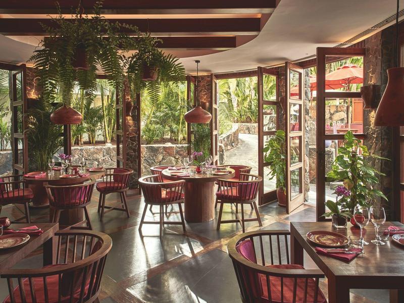 Acogedor restaurante con mesas de madera, sillas rojas y mucha luz natural a través de grandes ventanas.
