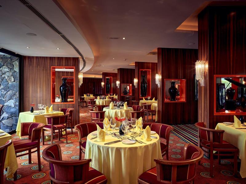 Restaurante elegante con mesas redondas, decoración cálida de madera, ideal para una comida sofisticada.