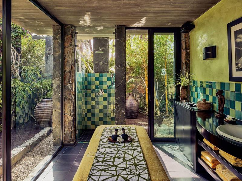 Amplio baño con azulejos verde-azulados, ventanales y vista al jardín.