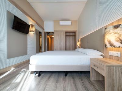 Modernes Hotelzimmer mit Doppelbett, Holzmöbeln und Wandfernseher, hell und einladend.