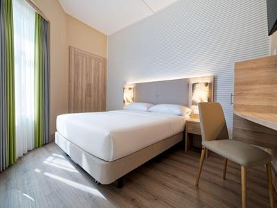 Modernes Hotelzimmer mit Doppelbett, Holzmöbeln und hellem Boden.