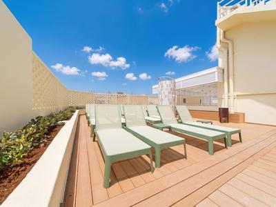 Dachterrasse mit Sonnenliegen, hölzernem Boden und blauen Himmel mit Wolken.