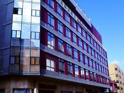 Moderní vícepodlažní hotel s velkými okny za jasného dne.