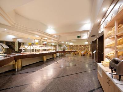 Prostorná hotelová bufetová místnost s potravinovými stojany, regály a teplým osvětlením.