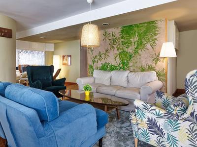 Cozy living room with blue armchairs, white sofa, and colorful floral chair.