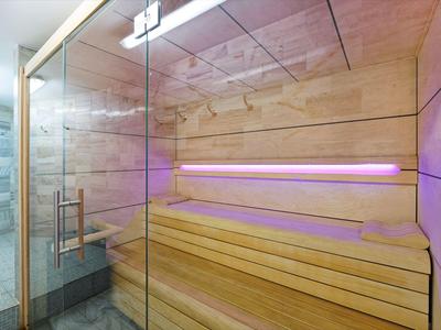 Modern sauna interior with wooden walls and benches, glass front, and relaxing lighting