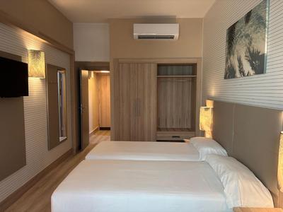 Modernes Hotelzimmer mit zwei Einzelbetten, großem Spiegel und offenem Kleiderschrank.