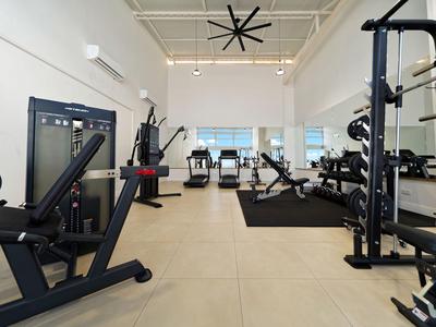 Moderner Hotel-Fitnessraum mit verschiedenen Trainingsgeräten und großer Deckenbelüftung.