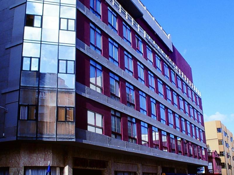 Moderní vícepodlažní hotel s velkými okny za jasného dne.