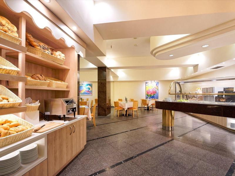 Prostorná snídaňová bufetová oblast s pečivem a moderní jídelnou v hotelu.
