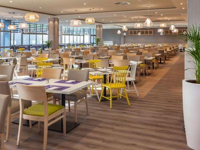 Helles modernes Restaurant mit Holzfußboden, gemischten Stühlen und großen Fenstern.