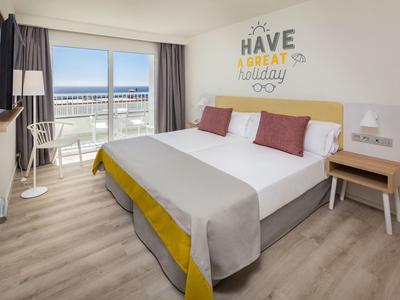 Modernes Hotelzimmer mit Doppelbett, Holzfußboden, Balkon und Meerblick bei Tageslicht.