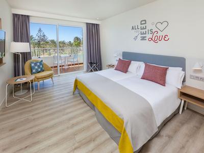 Modern hotel room with large bed, balcony, and light wooden floor