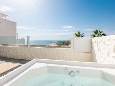 Whirlpool auf einer Terrasse mit Blick auf das Meer und blauem Himmel.