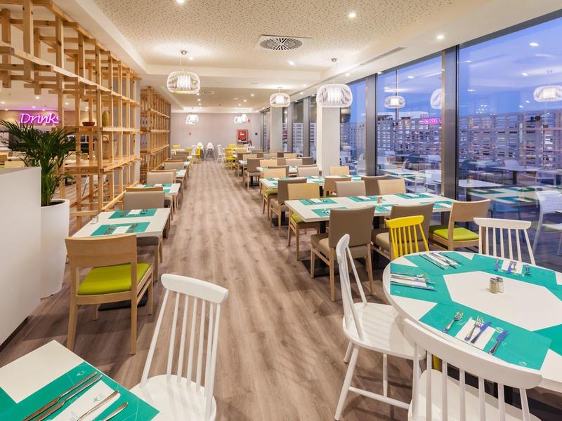 Světla restaurace s moderním nábytkem a velkými okny s výhledem na město.