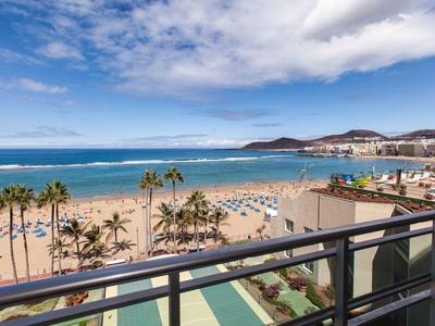 Strand met palmbomen en parasols gezien vanaf een balkon met uitzicht op de zee.