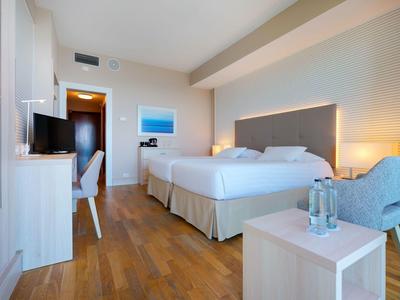 Modern ingerichte hotelkamer met twee bedden, bureau en zithoek.