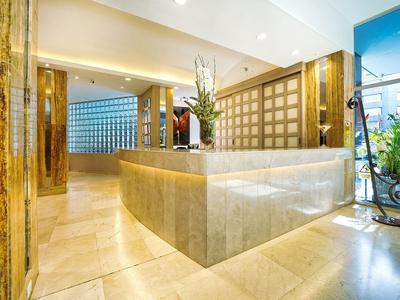Moderna hall dell'hotel con banco reception in pietra e pannelli di legno alle pareti.