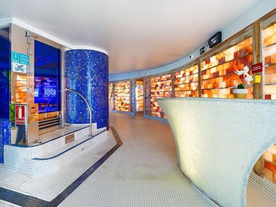 Moderna hall dell'hotel con pareti curve, reception illuminata e aree di seduta a gradini.