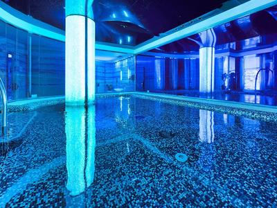 Piscina interna moderna dell'hotel con illuminazione blu e piastrelle lisce.