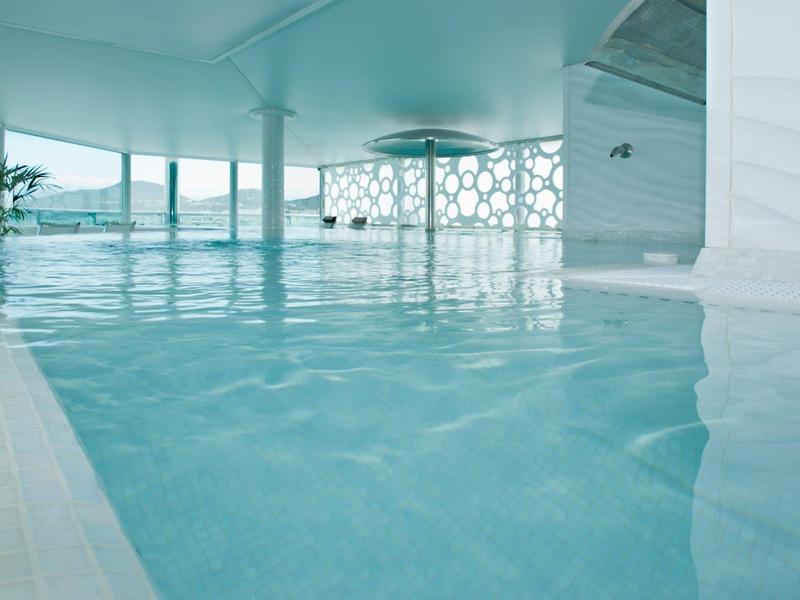 Binnenzwembad met grote ramen en witte architectonische details in een modern hotel.