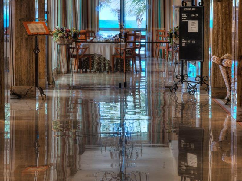 Glanzende marmeren gang met houten stoelen en uitzicht op raam bij Restaurante Roma.