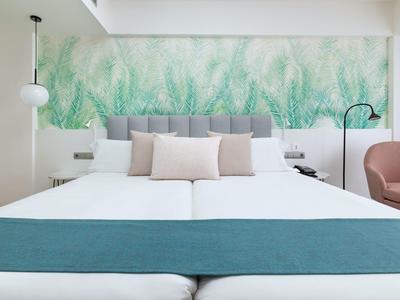 Chambre d'hôtel moderne avec deux lits, fresque végétale et décoration minimaliste.