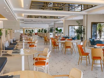 Hell eingerichteter Speisesaal mit orangefarbenen Stühlen und Tischdekoration in einem Hotel.