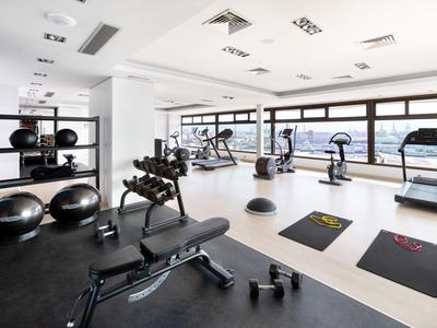 Modernes Fitnessstudio mit Trainingsgeräten und großen Fenstern in einem Hotel.