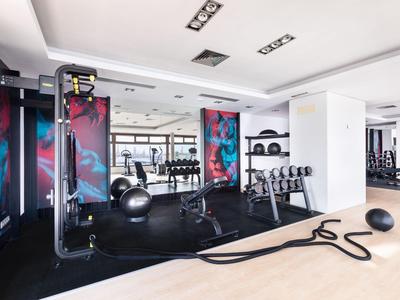 Helle Hotel-Fitnessstudio mit modernen Geräten und Yogabällen auf schwarzen Matten.
