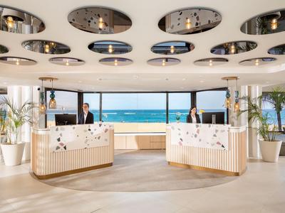 Helles Hotel-Lobby mit moderner Rezeption und Meeresblick.