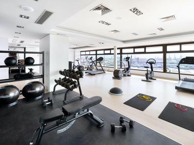 Gimnasio moderno con equipos, esterillas y grandes ventanas con vista.