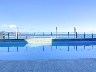 Une piscine tranquille avec vue sur l'océan sous un ciel bleu clair.