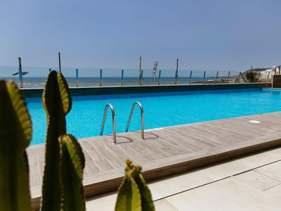 Piscina con cubierta de madera y vista al mar, cactus en primer plano