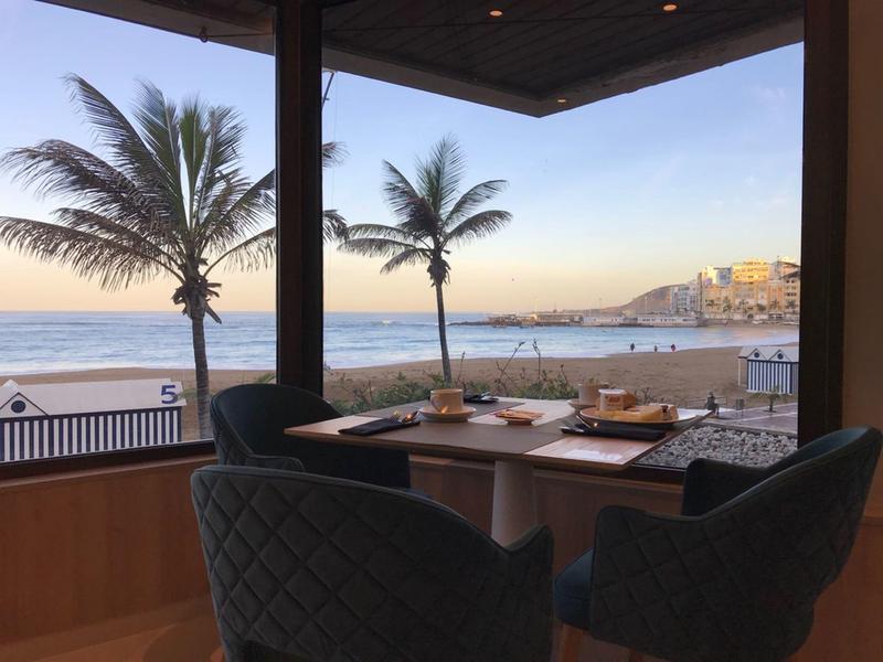Vue sur l'océan et les palmiers depuis une table à manger confortable dans un restaurant d'hôtel
