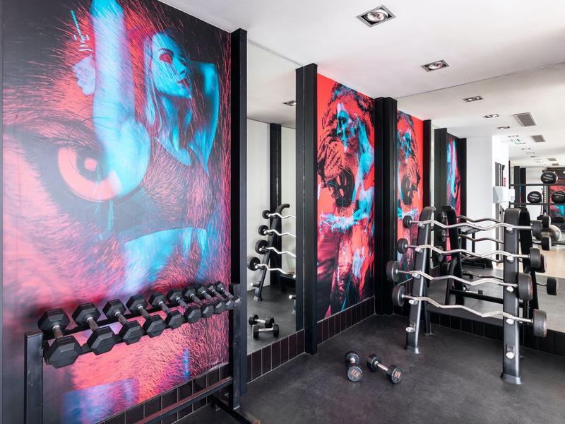 Salle de sport moderne avec poids libres et art mural coloré dans un hôtel.