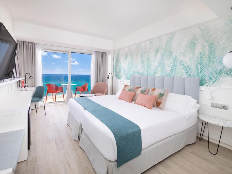 Chambre d'hôtel moderne avec lit double, balcon et vue sur mer en plein jour.