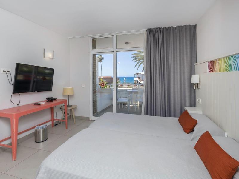 Nowoczesny pokój hotelowy z łóżkiem podwójnym, balkonem i widokiem na morze.