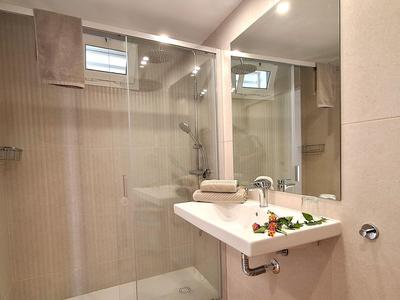 Moderne hotelbadkamer met inloopglazen douche en witte wastafel met handdoeken.