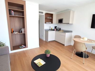Modern ingerichte hotelkamer met kitchenette, eetgedeelte en gezellige zitgelegenheid.
