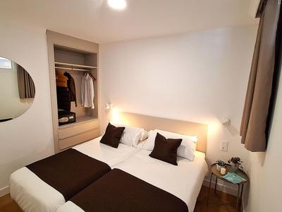 Modern ingerichte slaapkamer met tweepersoonsbed, nachtkastje en open kast.