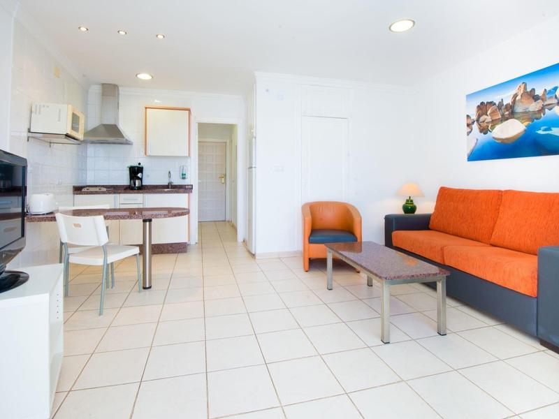 Modern eingerichtetes Wohnzimmer mit orangefarbenem Sofa und Esstisch in einem weißen Raum.