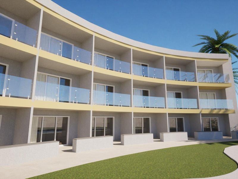 Modernes, dreistöckiges Gebäude mit geschwungenem Glasbalkon und Palmen bei blauem Himmel.