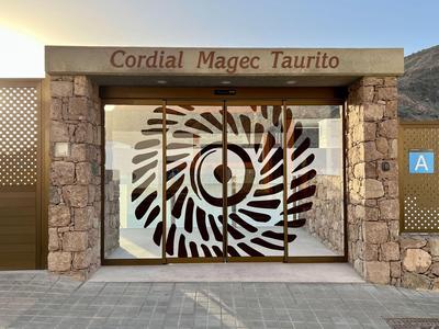 Entrée d'hôtel avec façade vitrée et motif spiral décoratif en pierre et verre.