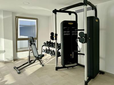 Salle de fitness lumineuse avec équipements modernes, fenêtre pour lumière naturelle et sol neutre.