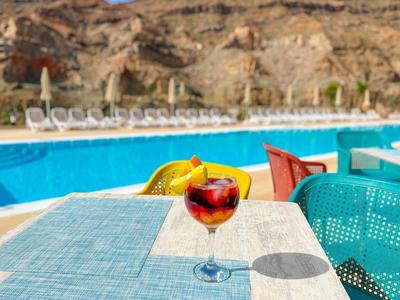 Verre à cocktail sur table près de la piscine avec vue sur les rochers et les chaises longues.