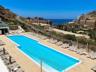 Grande piscine extérieure avec chaises longues dans un complexe hôtelier avec vue sur la mer.