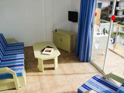 Sala luminosa con sofás a rayas azules, mesa pequeña y vista al balcón con barandilla.