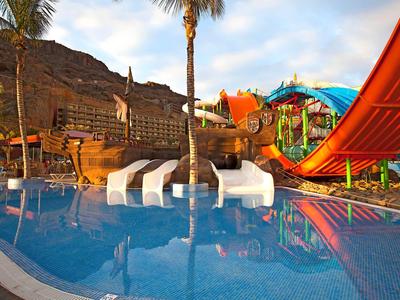 Parc aquatique coloré avec piscine, toboggans et palmiers sur fond rocheux.