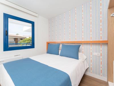 Piccola camera con letto matrimoniale, decorazioni blu e finestra con vista esterna.